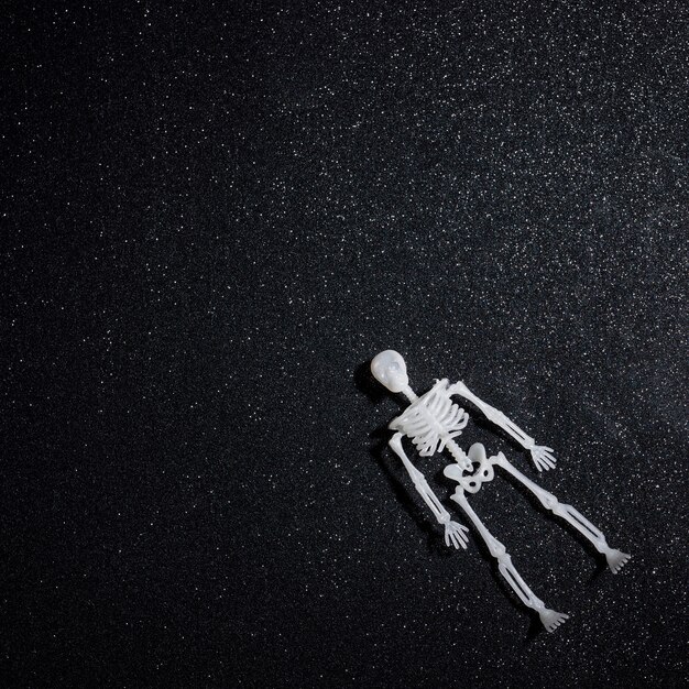 Floating skeleton over black glitter background