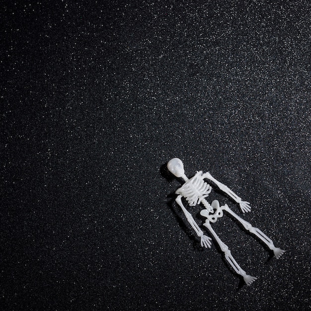 Floating skeleton over black glitter background