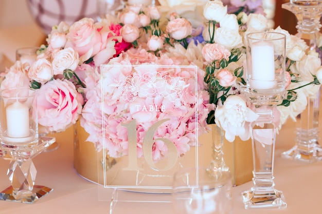 Floral composition and transparent glass engraving plate between candles