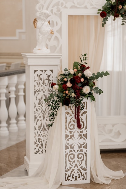 Floral composition on the white arch in the wedding ceremonial hall