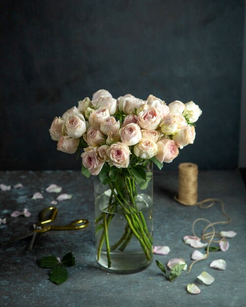 floral decor light pink roses in vase scissors rope and rose petals on black