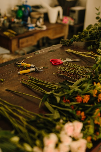 テーブルの上にハサミと花を持つ花のデザインスタジオ