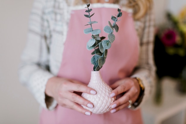 Florist in apron with plant in vase