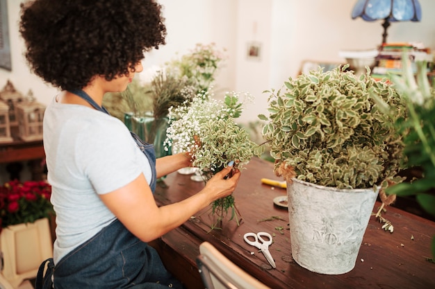 木製の机の上に白い花の植物を並べるフローリスト