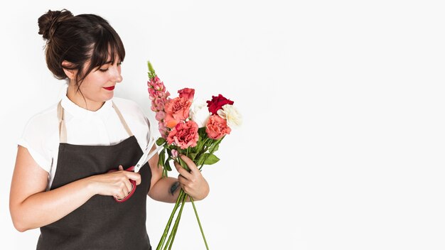 Florist cutting twigs of flowers with scissors on white backdrop