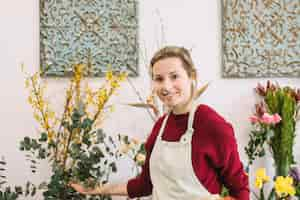 Free photo florist showing flowers and looking at camera