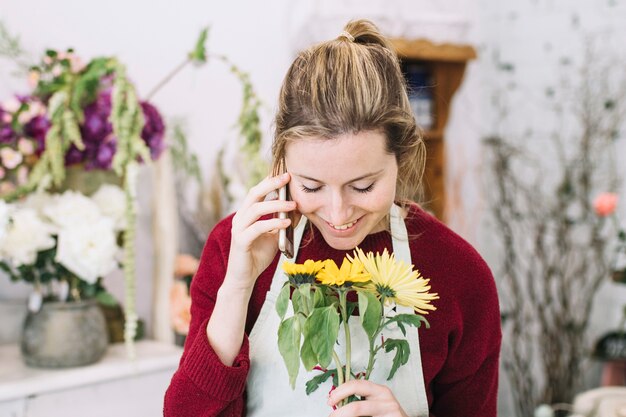 Florist smelling flower while speaking on smartphone