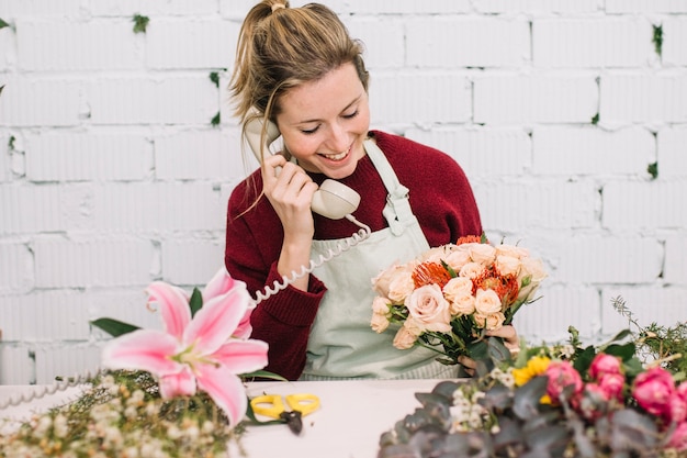 Florist with nice bouquet speaking on phone