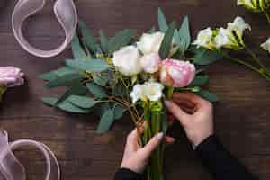 Free photo florist woman making fashion modern bouquet of different flowers on wooden background