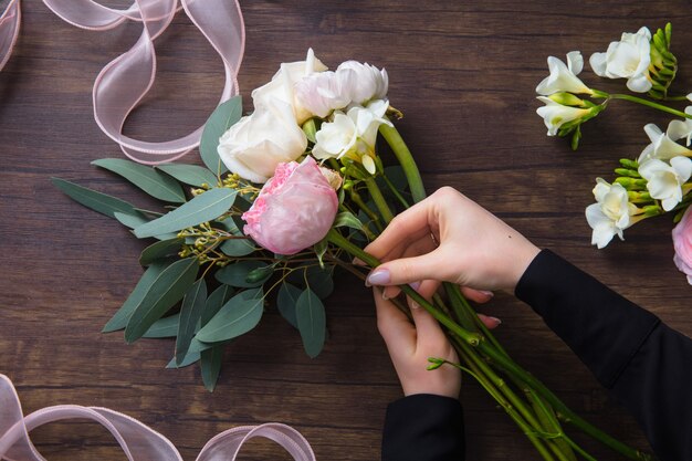 Florist at work: woman making fashion modern bouquet of different flowers on wooden table