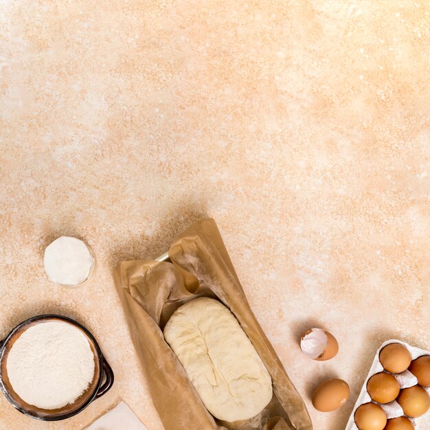 Flour; egg; kneaded dough on beige textured backdrop
