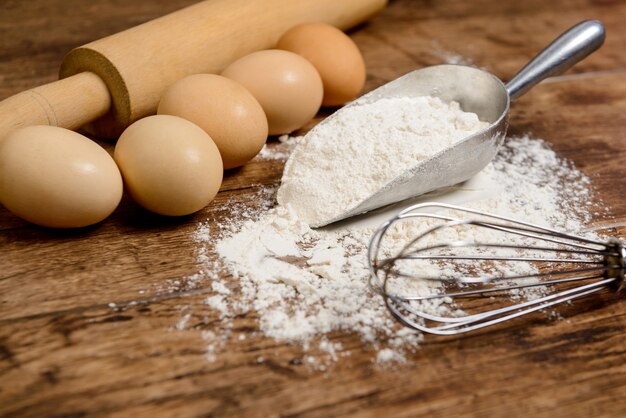 Flour, eggs and rolling pin on wooden table