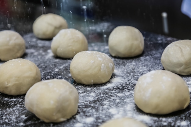 Free photo flour pouring on formed dough bolls on black board side view