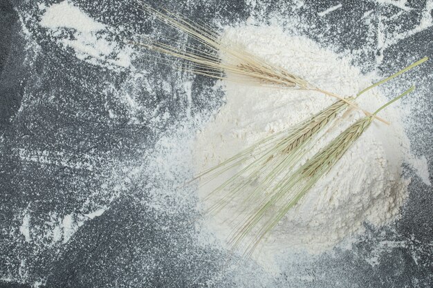 Flour with ears of wheat on marble surface. 