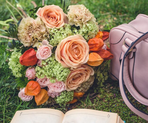 Flower bouquet on the grass, tote bag and a book 