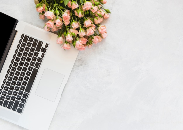 Free photo flower bouquet on laptop against concrete backdrop