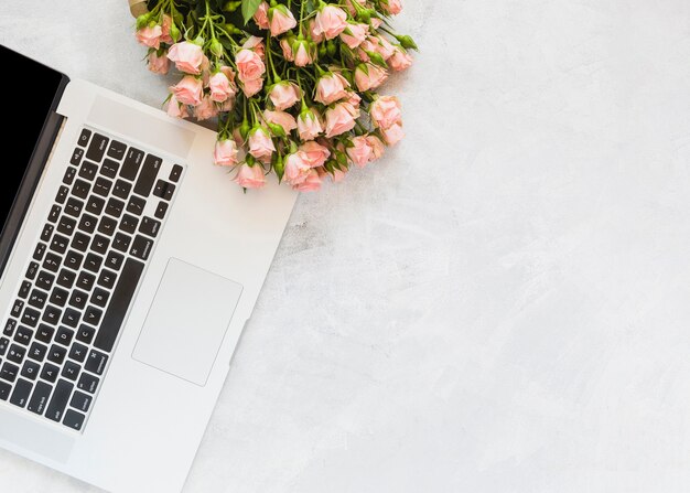 Flower bouquet on laptop against concrete backdrop