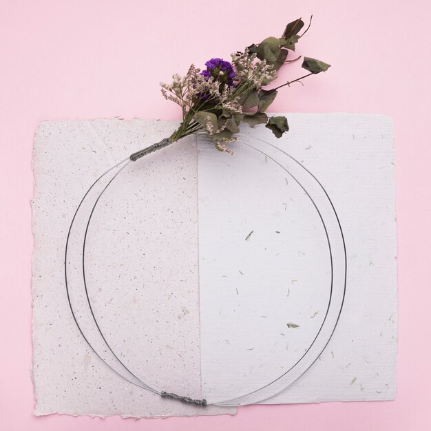 Букет цветов на круглом кольце над бумагой на розовом фоне