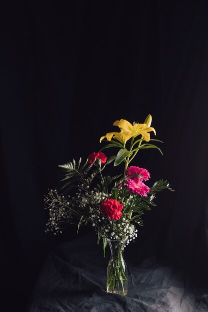 Flower bouquet in vase on dark textile