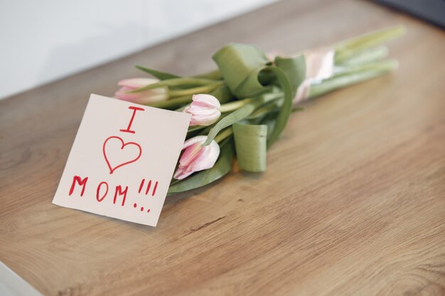 Букет цветов с поздравительной мамой для мамы на деревянном столе