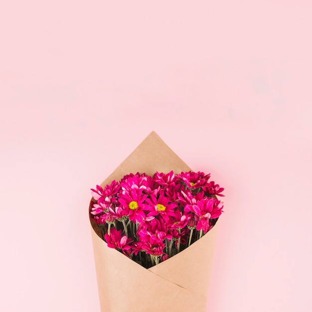 무료 사진 분홍색 배경에 갈색 종이로 감싸 인 꽃 꽃다발