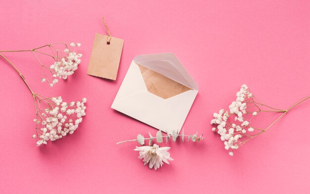 ピンクのテーブルの上の封筒と花の枝