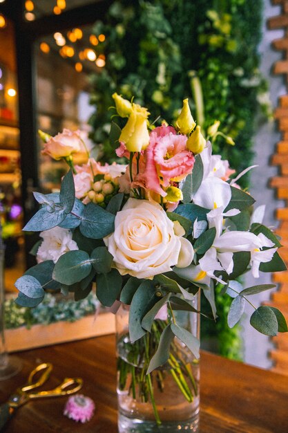 Flower composition in glass vase white and orange lithianthus roses side view