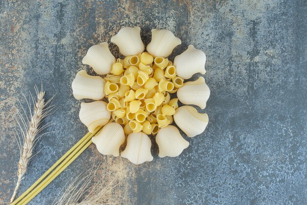 Flower made in pastas and wheat spike, on the marble background.