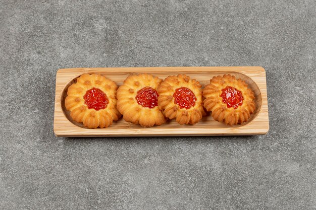 Flower shaped biscuits with jelly on wooden board