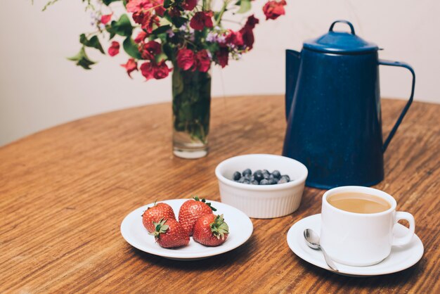 Flower vase; berries and coffee cup on table