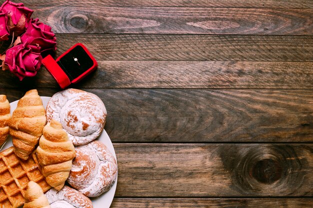 Flowers, bakery on dish and ring in gift box