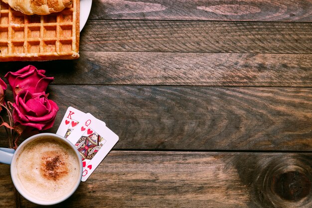 Flowers, bakery on plate, playing cards and cup of drink