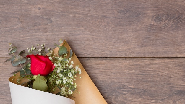 Flowers bouquet in pack paper on wooden table 