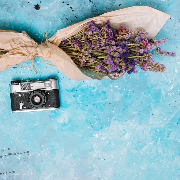 Flowers bouquet with camera on blue table