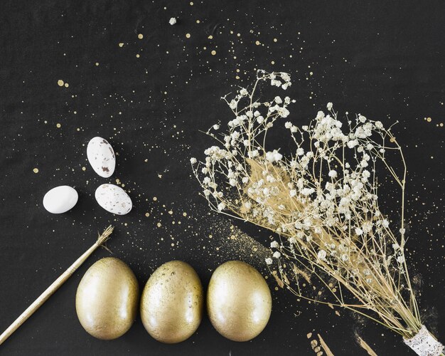 Цветы и щетка возле золотых яиц