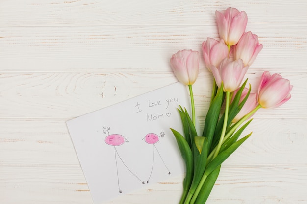 Flowers bunch and child drawing on wooden desk