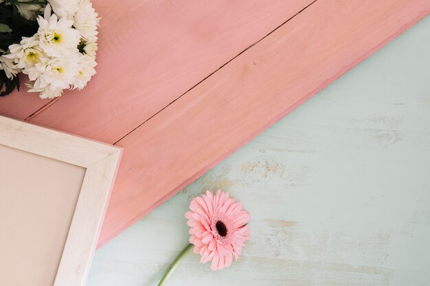 Flowers and frame on pink surface