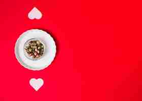 Free photo flowers in glass on plate near ornament hearts