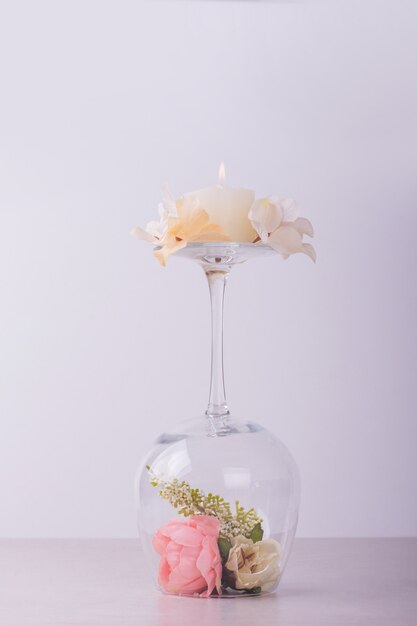 Flowers inside wine glass and candle.