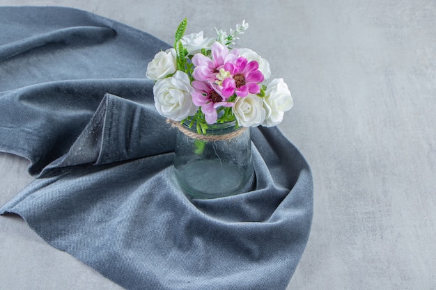 Flowers in a jar on a piece of fabric , on the white background. High quality photo