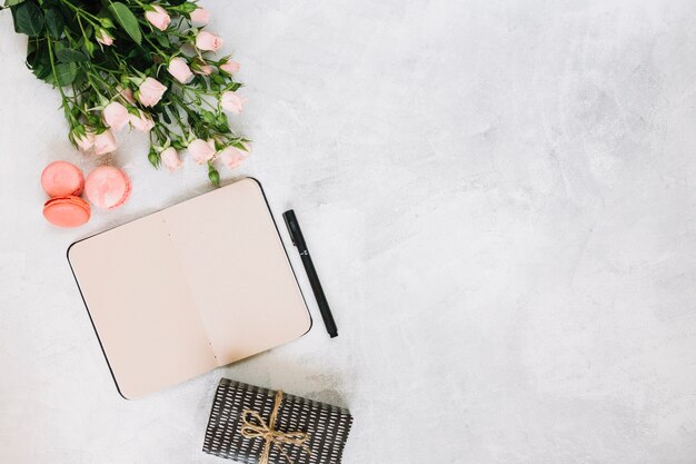 Flowers and macaroons near notepad and gift