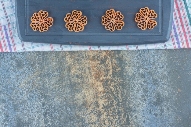 Flowers made from macaroni on board, on the towel, on the marble surface.