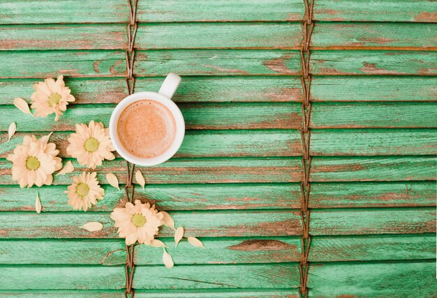 Flowers near the coffee cup on wooden background