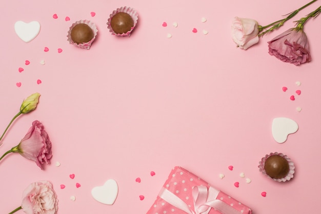 Flowers near present box and chocolate candies