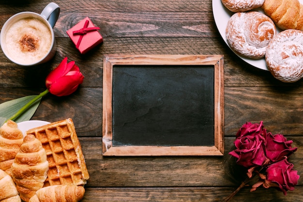 Fiori, cornice per foto, panetteria su piatti, confezione regalo e tazza di bevanda