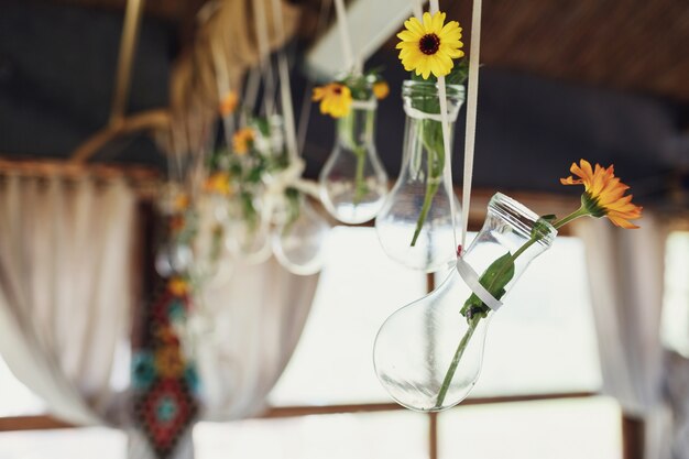 "Flowers in small vases hanging on ropes"