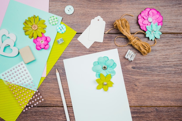 Flowers on white paper with pencil; tags; flower and rope on wooden desk