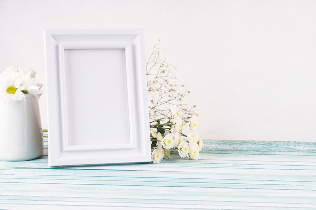 Flowers with blank frame on table