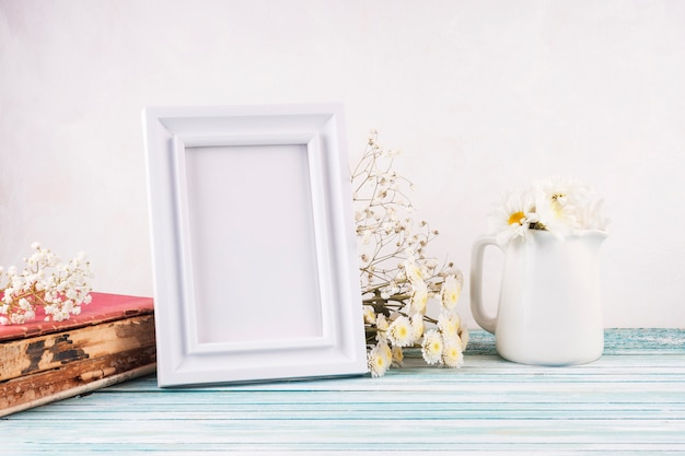 Flowers with blank frame on wooden table