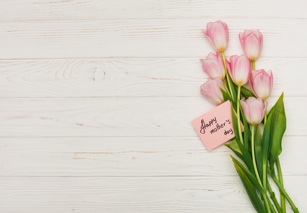 Flowers with Happy Mothers Day card on table 